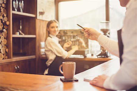 pouring cappuccino - Professional barista. Young woman in apron working at bar counter with coffee machine. Man taking order Photographie de stock - Aubaine LD & Abonnement, Code: 400-09018956