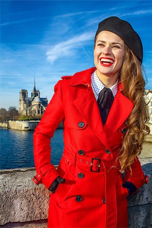simsearch:400-09031587,k - Bright in Paris. smiling modern traveller woman in red trench coat on embankment in Paris, France looking into the distance Stock Photo - Budget Royalty-Free & Subscription, Code: 400-09019005