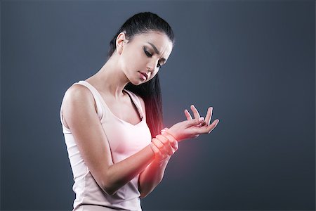 simsearch:400-06476910,k - Body pain. Studio shot of beautiful young woman with dark brown hair. Woman suffering from wrist pain. Red spot on wrist Stock Photo - Budget Royalty-Free & Subscription, Code: 400-09019073