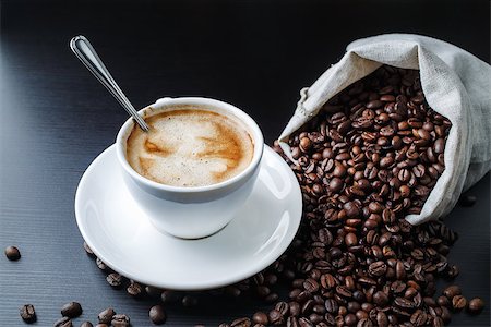 simsearch:6109-08536940,k - Coffee cup, saucer and coffee beans scattered from a canvas bag on black wooden table. Stock Photo - Budget Royalty-Free & Subscription, Code: 400-09010374