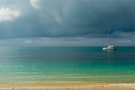 simsearch:400-07245917,k - A gloomy sky above the turquoise calm sea and a small white yacht Fotografie stock - Microstock e Abbonamento, Codice: 400-09010738