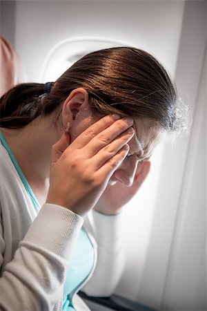 A woman with a migraine near a window in an airplane Foto de stock - Super Valor sin royalties y Suscripción, Código: 400-09010871