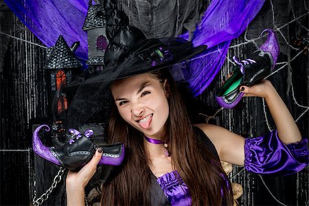 simsearch:400-07776243,k - horizontal portrait of a cheerful witch with shoes in hands on a black background Fotografie stock - Microstock e Abbonamento, Codice: 400-09011628