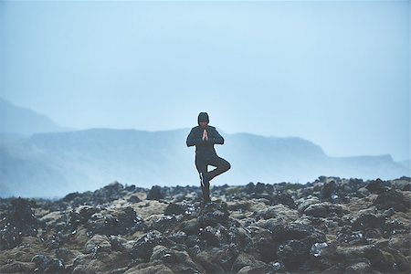 simsearch:400-08556910,k - Woman in waterproof clothing stands in yoga pose on volcanic Lava fields on background of mountains of Iceland. Stock Photo - Budget Royalty-Free & Subscription, Code: 400-09011759