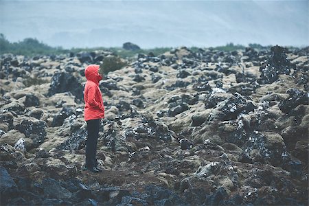 simsearch:400-08556910,k - Woman in waterproof clothing walks on volcanic Lava fields on background of mountains of Iceland. Stock Photo - Budget Royalty-Free & Subscription, Code: 400-09011760