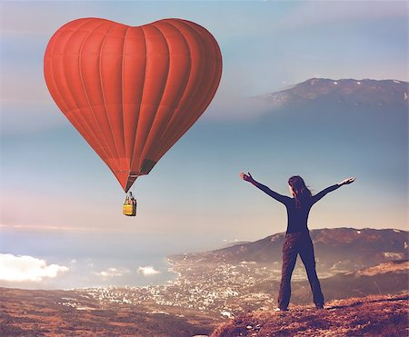 simsearch:400-09090841,k - Girl with rised hands on the top of mountain looking at big red air balloon heart shape flying in blue sky. Romantic on Valentine's Day. Sport and recreation travel theme. Nature background. Back view Stock Photo - Budget Royalty-Free & Subscription, Code: 400-09028404