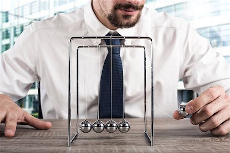 Businessman plays with the pendulum of Newtown balls Stock Photo - Budget Royalty-Free & Subscription, Code: 400-09028897