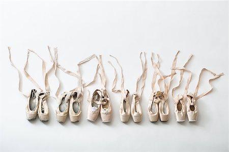 simsearch:400-09029135,k - Many pairs of ballet shoes in pairs stand in a row. Pointe shoes in different condition from new to very shabby old. Tapes are accurately laid out in different directions. Studio shooting, horizontal top shot. Stock Photo - Budget Royalty-Free & Subscription, Code: 400-09029132