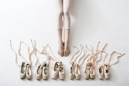 simsearch:400-09029135,k - Many pairs of ballet shoes in pairs stand in a row. Legs of a young ballerina with bare feet. The girl's fingers are all covered in wounds and plasters. Pointe shoes in different condition from new to very shabby old. Tapes are accurately laid out in different directions. Horizontal. Stock Photo - Budget Royalty-Free & Subscription, Code: 400-09029133