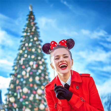 DISNEYLAND, FRANCE - DECEMBER, 8, 2016: smiling stylish woman in red trench coat in the front of big Christmas tree Stock Photo - Budget Royalty-Free & Subscription, Code: 400-09029629