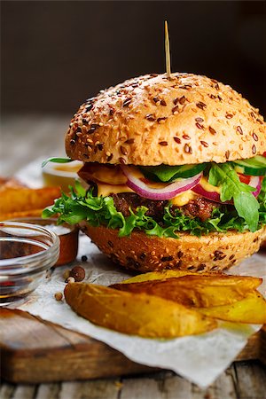 Tasty beef burger with lettuce and mustard and french fries served on cutting board on a rustic wooden table Stock Photo - Budget Royalty-Free & Subscription, Code: 400-09064446