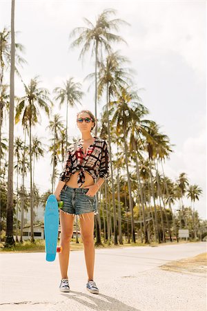 Stylish hipster lady in short denim shorts, shirt and sunglasses stay on tropic street with her short board skateboard on a sunny hot summer day. Swag urban teen girl. Outdoor lifestyle portrait. Stock Photo - Budget Royalty-Free & Subscription, Code: 400-09064513