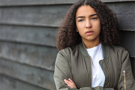 Beautiful mixed race African American girl teenager female young woman outside wearing a green bomber jacket looking sad depressed or thoughtful Stock Photo - Budget Royalty-Free & Subscription, Code: 400-09067454