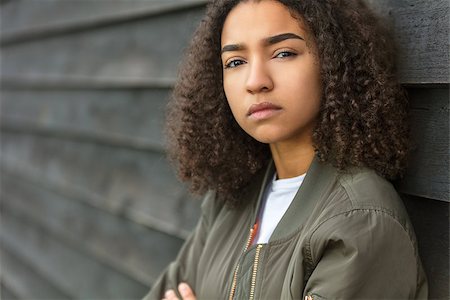 Beautiful mixed race African American girl teenager female young woman outside wearing a green bomber jacket looking sad depressed or thoughtful Stock Photo - Budget Royalty-Free & Subscription, Code: 400-09069152