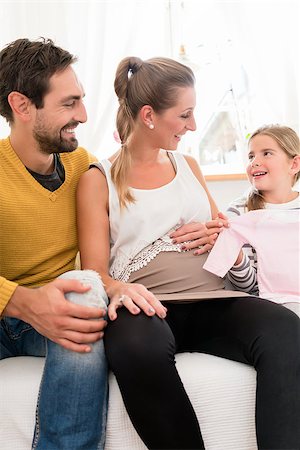 simsearch:400-08253730,k - Mother, father and daughter awaiting family addition and looking at baby clothes Stock Photo - Budget Royalty-Free & Subscription, Code: 400-09062608