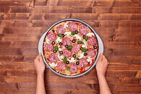 simsearch:695-05772884,k - Woman hands holding pizza ready to bake in the baking pan - top view with copy space Stockbilder - Microstock & Abonnement, Bildnummer: 400-09062916