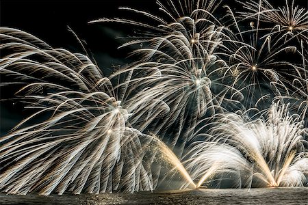 Details of Fireworks on the lakefront of Luino over the Maggiore Lake in a summer evening with blue sky and mountains in the background Stock Photo - Budget Royalty-Free & Subscription, Code: 400-09063199