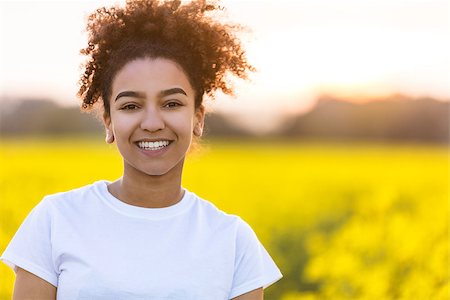 simsearch:400-04068097,k - Outdoor portrait of beautiful happy mixed race African American girl teenager female young woman smiling with perfect teeth in a field of yellow flowers Stockbilder - Microstock & Abonnement, Bildnummer: 400-09063321