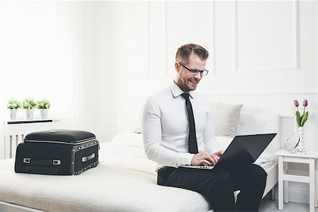 simsearch:6109-06195339,k - Young businessman on bed working with a laptop from his hotel room Photographie de stock - Aubaine LD & Abonnement, Code: 400-09063816