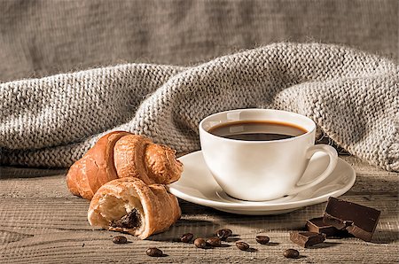 Coffee with croissants on the background of a woolen scarf. Grains of coffee next to the cup. Several pieces of dark chocolate next to each other. Stock Photo - Budget Royalty-Free & Subscription, Code: 400-09070939