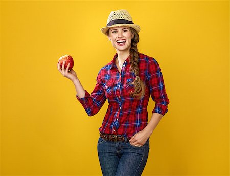 Healthy food to your table. happy modern woman grower in checkered shirt isolated on yellow background showing an apple Stock Photo - Budget Royalty-Free & Subscription, Code: 400-09084575