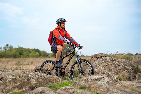 simsearch:400-09084281,k - Happy Cyclist in Red Resting on the Bike on the Rocky Trail. Adventure Sport and Travel Biking Concept. Fotografie stock - Microstock e Abbonamento, Codice: 400-09084598