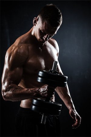 simsearch:400-05180877,k - Athletic shirtless young male fitness model makes exercises with dumbbells on dark background Stock Photo - Budget Royalty-Free & Subscription, Code: 400-09085118