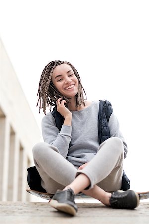 Attractive and smiling teenager girl relaxing with a skateboard and sitting down, talking to somebody on phone, outdoors. Stock Photo - Budget Royalty-Free & Subscription, Code: 400-09080711