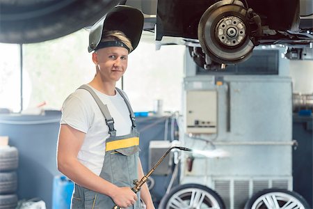Portrait of a young and handsome auto mechanic looking at camera with confidence while welding during work in a modern automobile repair shop Stock Photo - Budget Royalty-Free & Subscription, Code: 400-09082917