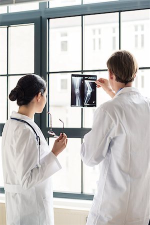 Experienced male orthopedist helping his female colleague with the interpretation of an X-ray of the knee of a patient in the office Fotografie stock - Microstock e Abbonamento, Codice: 400-09082918