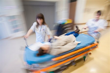 A litter with patient, pushed in emergency through modern hospital corridor by two nurses. Panned, motion blurred picture. Stock Photo - Budget Royalty-Free & Subscription, Code: 400-09082957