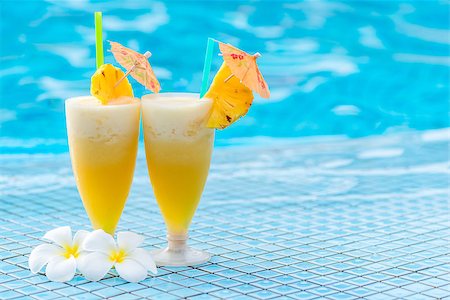 delicious pineapple cocktail beautifully decorated with umbrellas and flowers on the edge of the pool Stock Photo - Budget Royalty-Free & Subscription, Code: 400-09083926