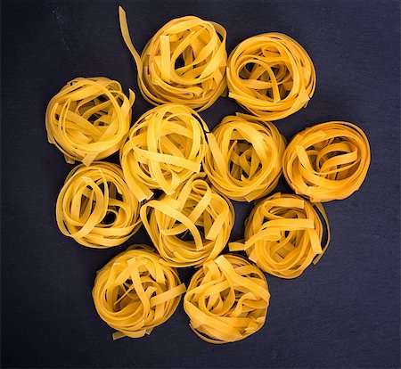 raw wheat pasta in the form of nests on a black background, top view Stock Photo - Budget Royalty-Free & Subscription, Code: 400-09119531