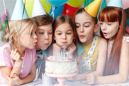 dreaming about eating - Festive children in party caps, blow candles on delicious cake, make wish, celebrate birthday, have party together, hold colourful balloons. Happy small girl spends festive event with best friends. Foto de stock - Super Valor sin royalties y Suscripción, Código: 400-09112321