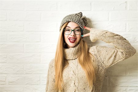 simsearch:400-08430017,k - Trendy Hipster Girl in Knitted Sweater and Beanie Hat Going Crazy at White Brick Wall Background. Funny Female. Casual Fashion Outfit in Winter. Toned Photo with Copy Space. Stock Photo - Budget Royalty-Free & Subscription, Code: 400-09112340