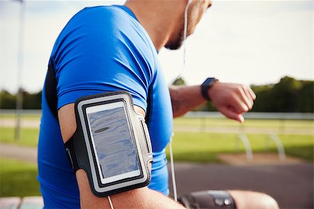 Male athlete wearing smartphone armband checking smartwatch Stock Photo - Budget Royalty-Free & Subscription, Code: 400-09121799