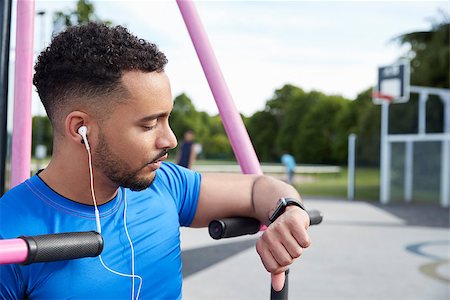 Young man at outdoor gym checking fitness app on smartwatch Stock Photo - Budget Royalty-Free & Subscription, Code: 400-09121804