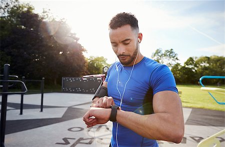 Young man at outdoor gym setting fitness app on smartwatch Stock Photo - Budget Royalty-Free & Subscription, Code: 400-09121805