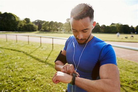 Young man at running track setting fitness app on smartwatch Stock Photo - Budget Royalty-Free & Subscription, Code: 400-09121806
