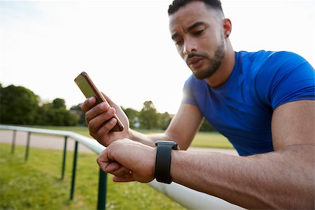 Male athlete using fitness app on smartphone and smartwatch Stock Photo - Budget Royalty-Free & Subscription, Code: 400-09121815
