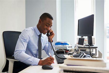 simsearch:693-03307925,k - Young black businessman using the phone at his office desk Photographie de stock - Aubaine LD & Abonnement, Code: 400-09121909