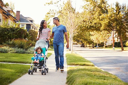 Couple Push Daughter In Stroller As They Walk Along Street Stock Photo - Budget Royalty-Free & Subscription, Code: 400-09122243