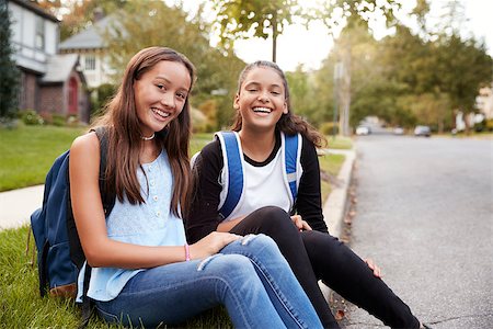Two teen girlfriends sit at the roadside looking to camera Stock Photo - Budget Royalty-Free & Subscription, Code: 400-09122442