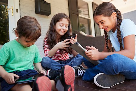 Group Of Children Sit On Porch Playing With Digital Devices Stock Photo - Budget Royalty-Free & Subscription, Code: 400-09122477