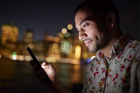 Man Using Mobile Phone At Night With City Skyline In Background Stock Photo - Budget Royalty-Free & Subscription, Code: 400-09122718