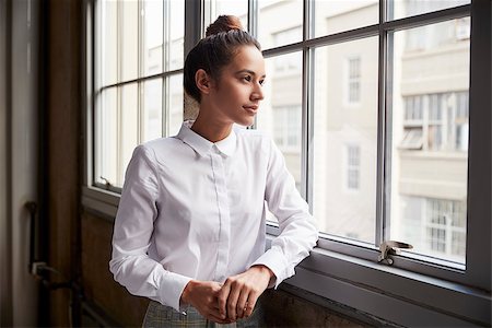 simsearch:400-08838779,k - Young woman with hair bun looking out of window, waist up Stock Photo - Budget Royalty-Free & Subscription, Code: 400-09122780