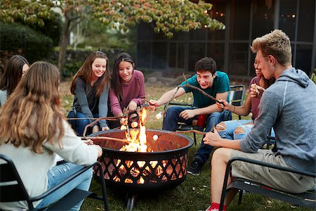 Teenage friends sit round a fire pit toasting marshmallows Stock Photo - Budget Royalty-Free & Subscription, Code: 400-09123042