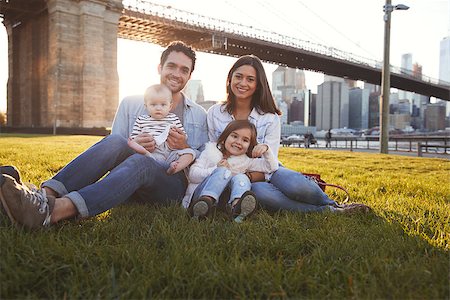 simsearch:400-09123158,k - Young family with two daughters sitting on lawn, close up Foto de stock - Royalty-Free Super Valor e Assinatura, Número: 400-09123190