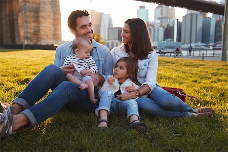 simsearch:400-09123158,k - Young family with two daughters sitting on lawn, close up Foto de stock - Royalty-Free Super Valor e Assinatura, Número: 400-09123191