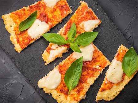 fascinadora (artist) - Top view of sliced homemade cauliflower pizza crust with mozarella and fresh basil on slate plate over black concrete background. Stock Photo - Budget Royalty-Free & Subscription, Code: 400-09132239